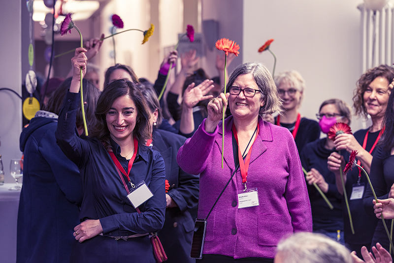 Gruppenfoto Frauen halten Blumen in die Luft und lachen
